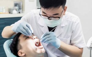 Asian dentist examining male asian patient teeth providing affordable and quality dental care