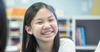 Cheerful young Asian girl enjoying English tuition in Singapore