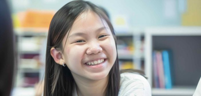 Cheerful young Asian girl enjoying English tuition in Singapore